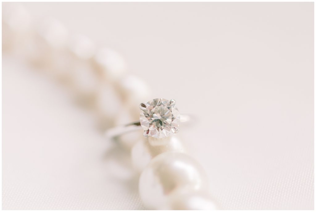 Katie's solitaire diamond engagement ring resting on her strand of pearls